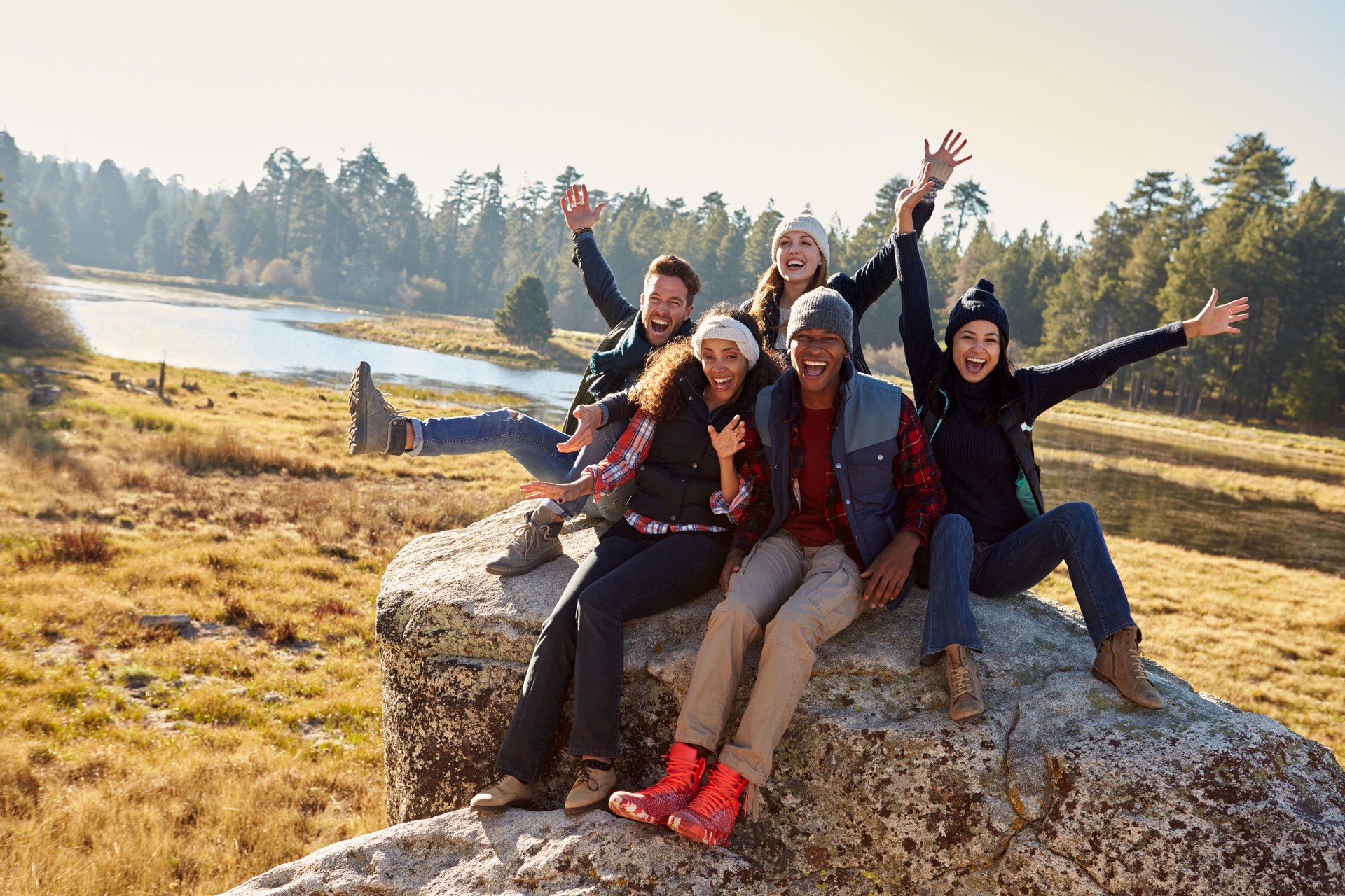 Portrait of five friends sitting on a rock in countryside